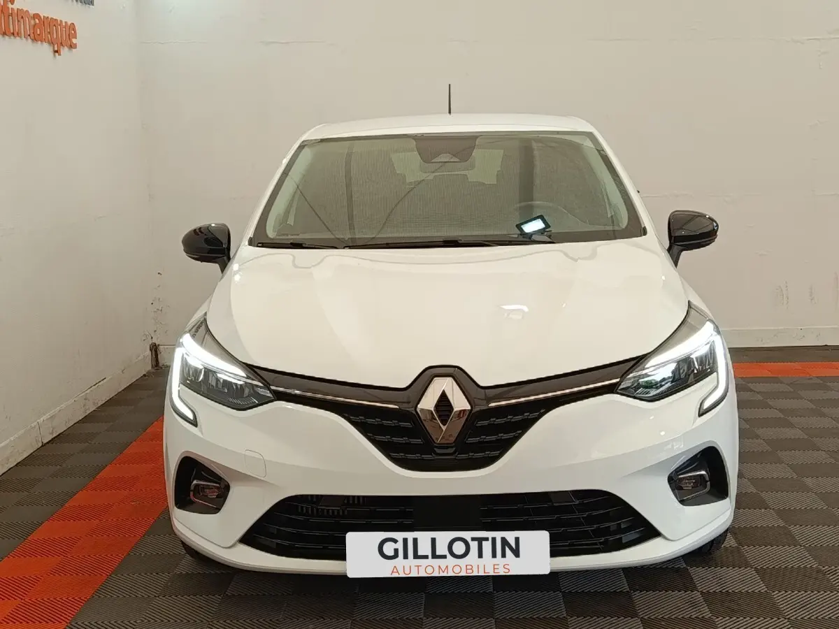 Vue avant d'une Renault Clio blanche 2023 avec feux LED allumés et rétroviseurs noirs contrastants.