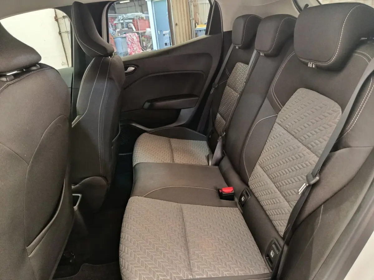 Vue intérieure côté gauche montrant la banquette arrière gris foncé avec motifs et ceintures de sécurité de la Renault Clio blanche.