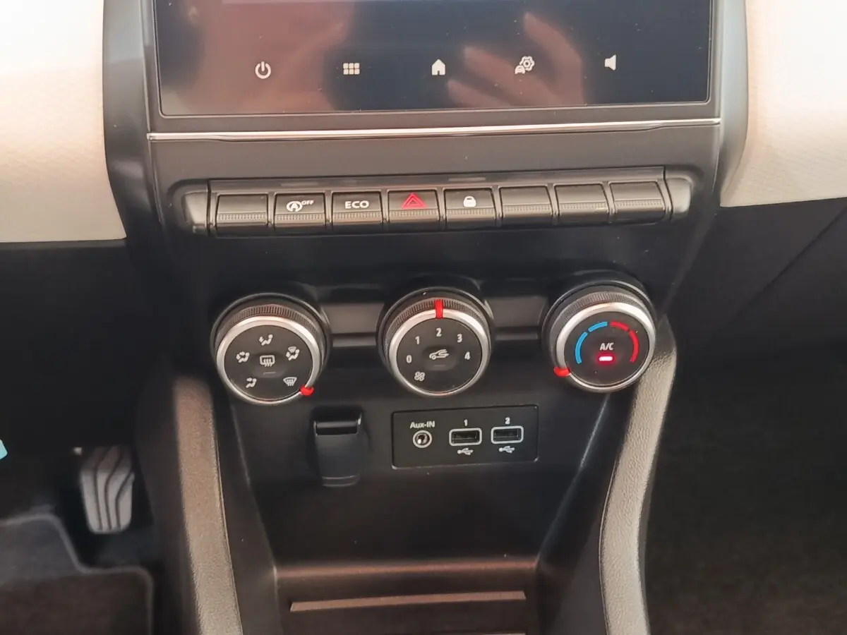 Vue rapprochée du tableau de bord central noir de la Renault Clio blanche 2023 avec commandes climatisation et ports USB.
