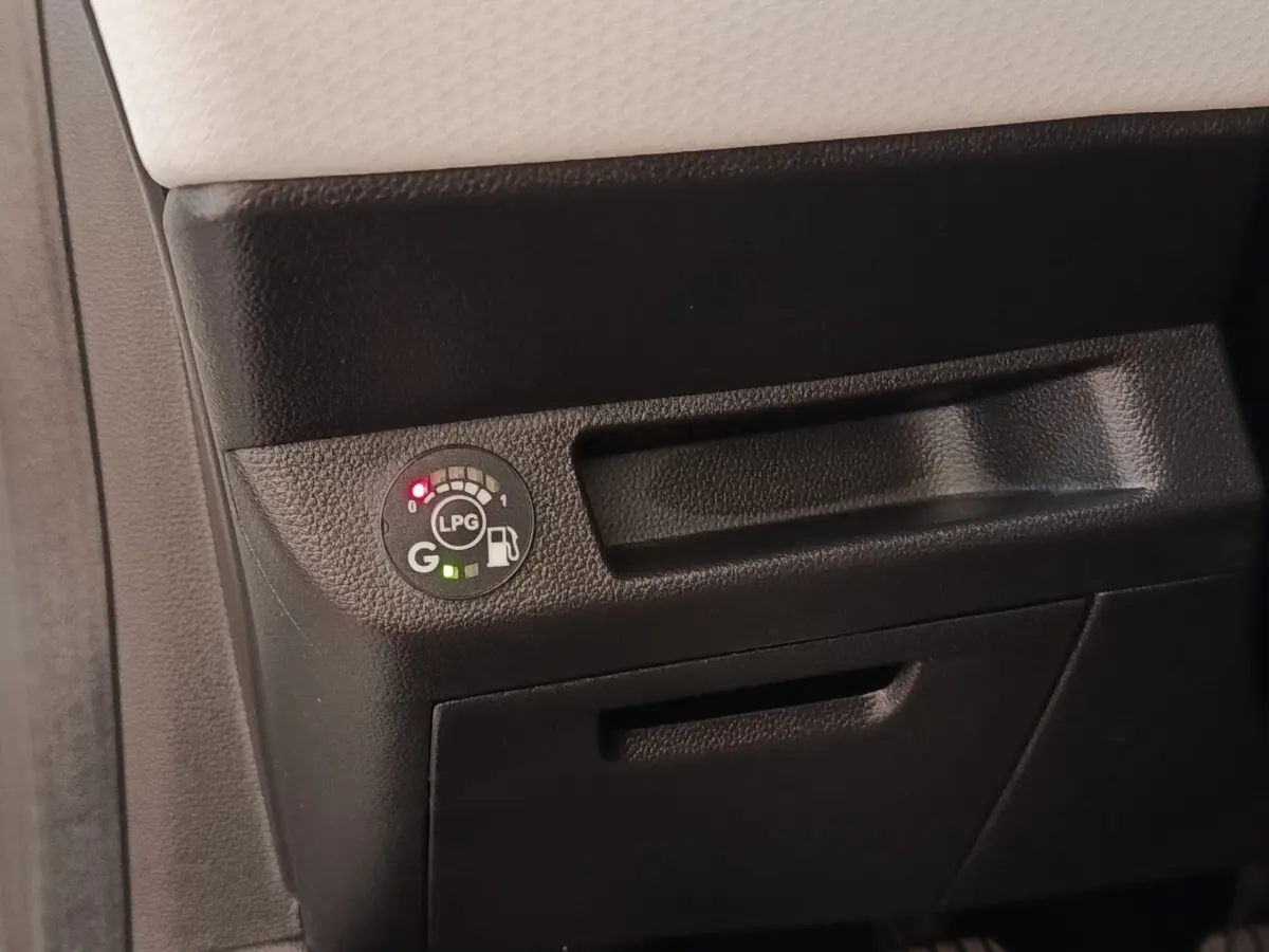 Gros plan sur le tableau de bord noir de la Renault Clio blanc, montrant l'indicateur de niveau GPL lumineux.