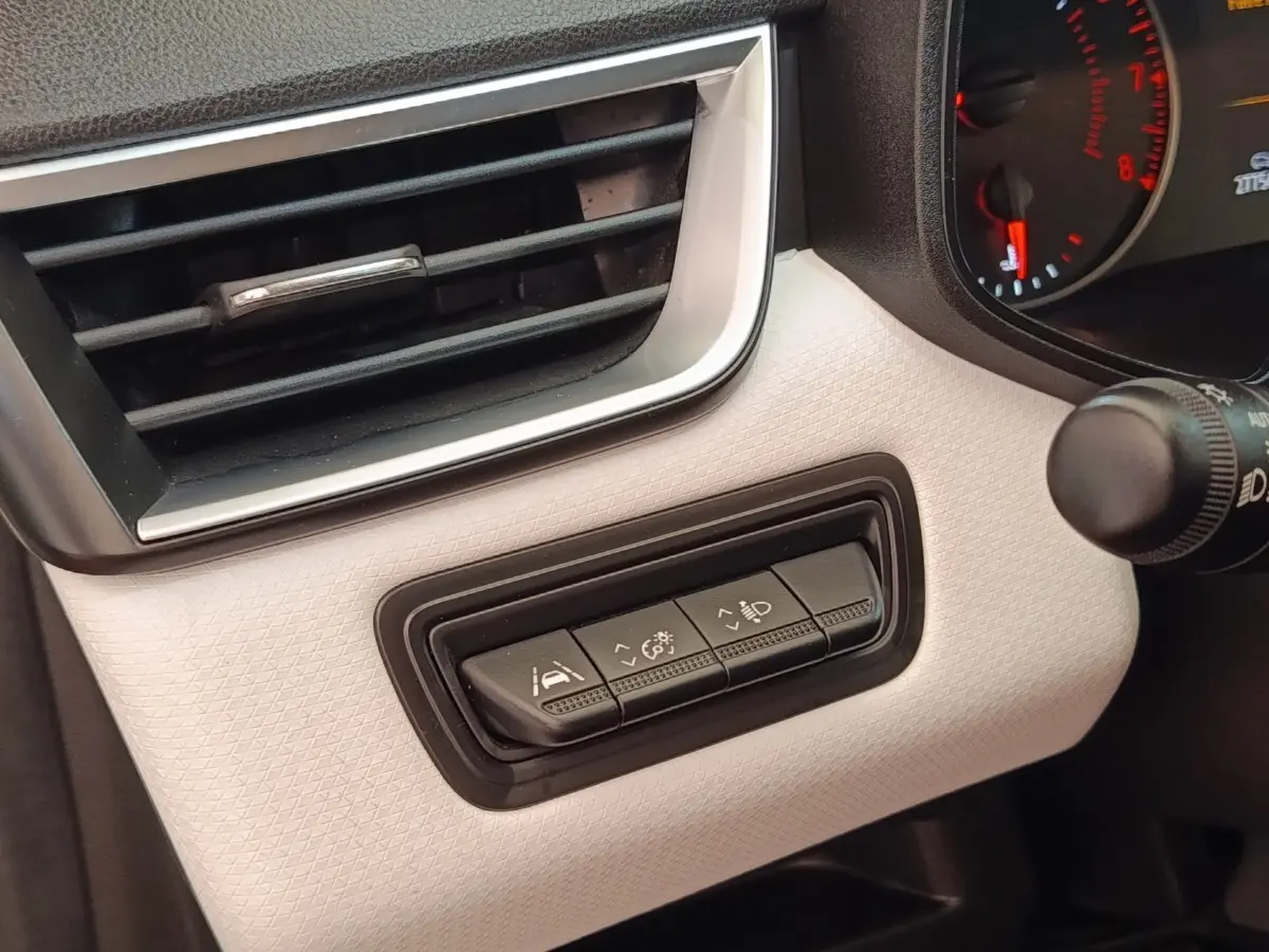 Gros plan sur les commandes d'assistance à la conduite à gauche du tableau de bord blanc de la Renault Clio Evolution TCe 100 GPL.