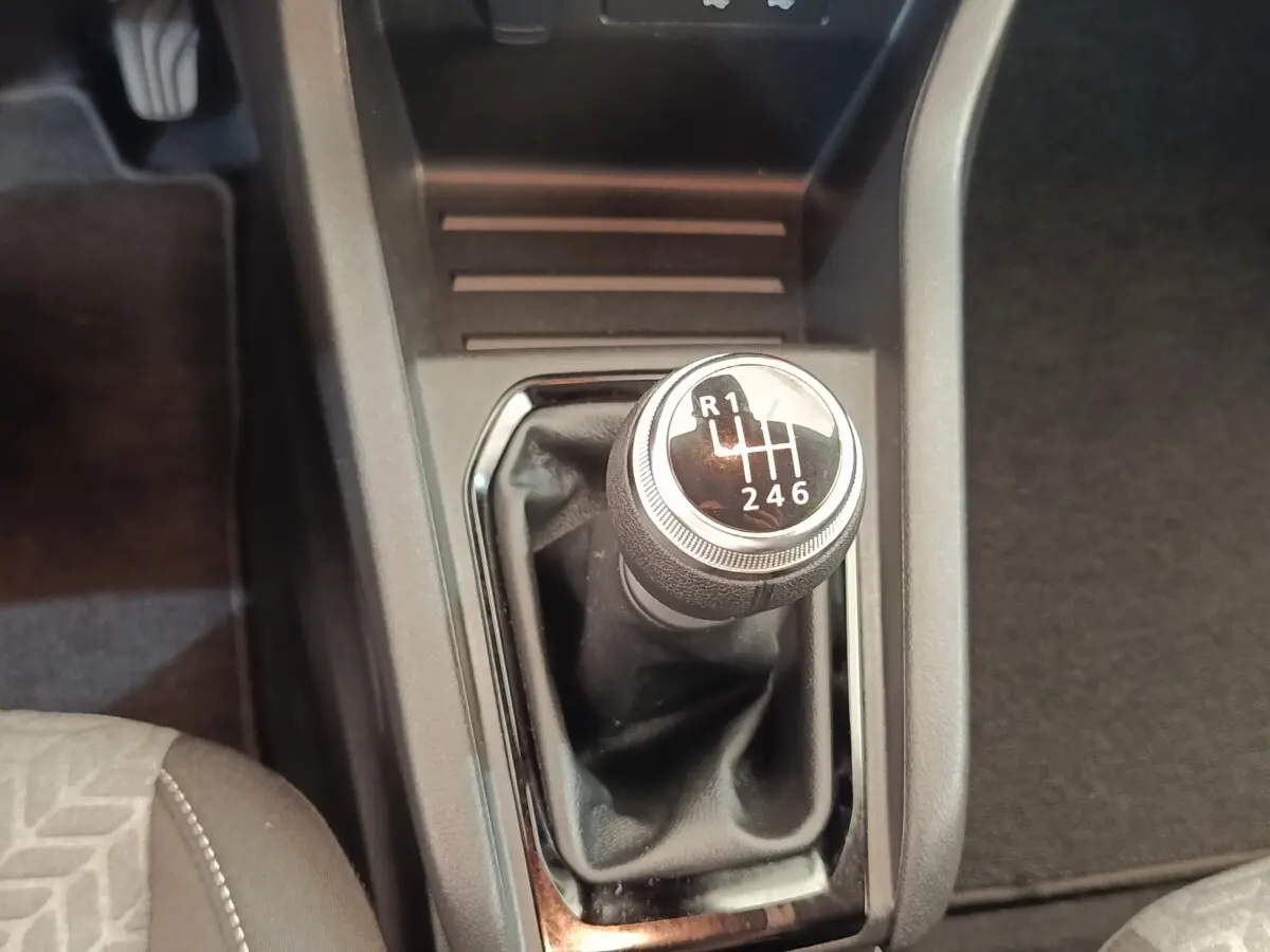 Gros plan sur le levier de vitesses manuel noir de la Renault Clio Evolution TCe 100 GPL 2023, intérieur sombre.