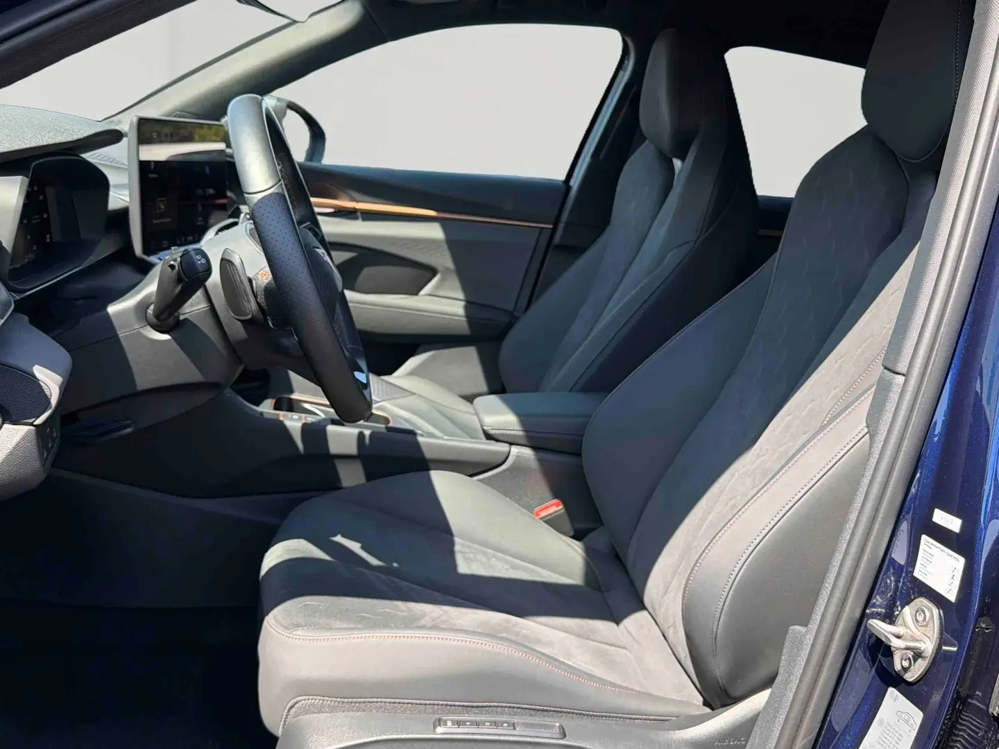 Vue intérieure côté conducteur du CUPRA Terramar bleu, sièges baquets suédine et cuir noir avec surpiqûres cuivrées.