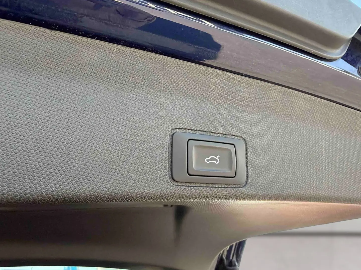 Bouton d'ouverture électrique du hayon sur la partie intérieure du coffre d'une CUPRA Terramar bleu.