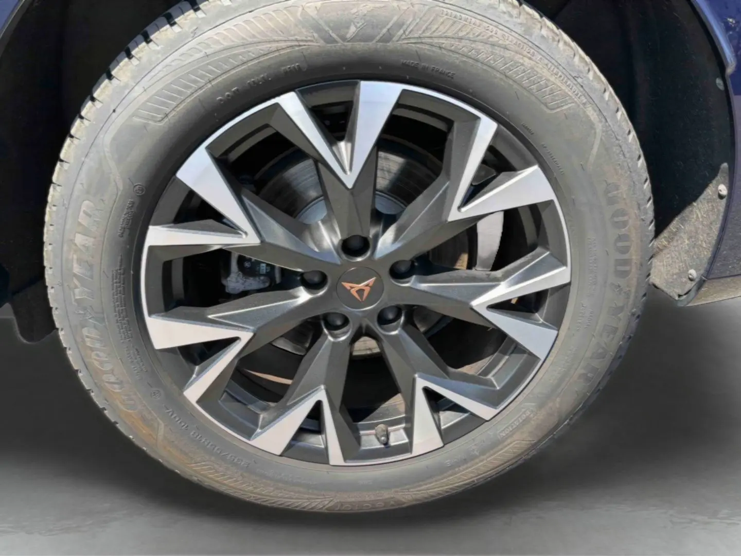 Gros plan sur la jante alliage gris anthracite à design géométrique du CUPRA Terramar bleu, avec logo CUPRA central cuivré.