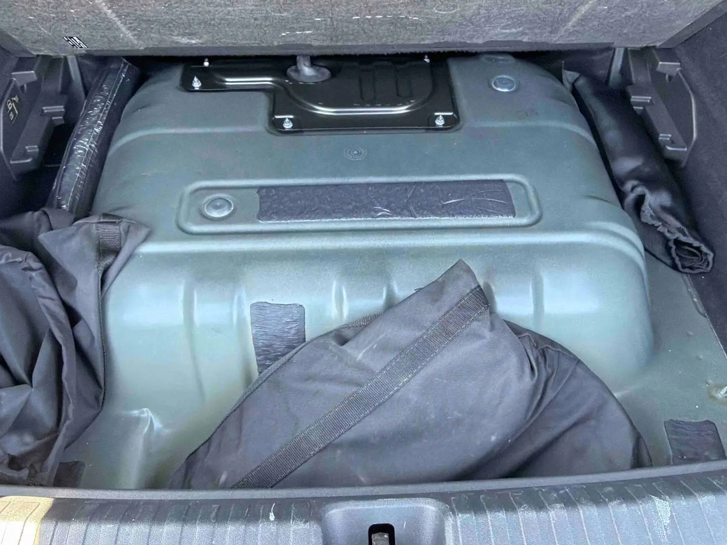Vue du coffre ouvert de la CUPRA Terramar 2025, montrant la batterie électrique et un sac noir partiellement visible.