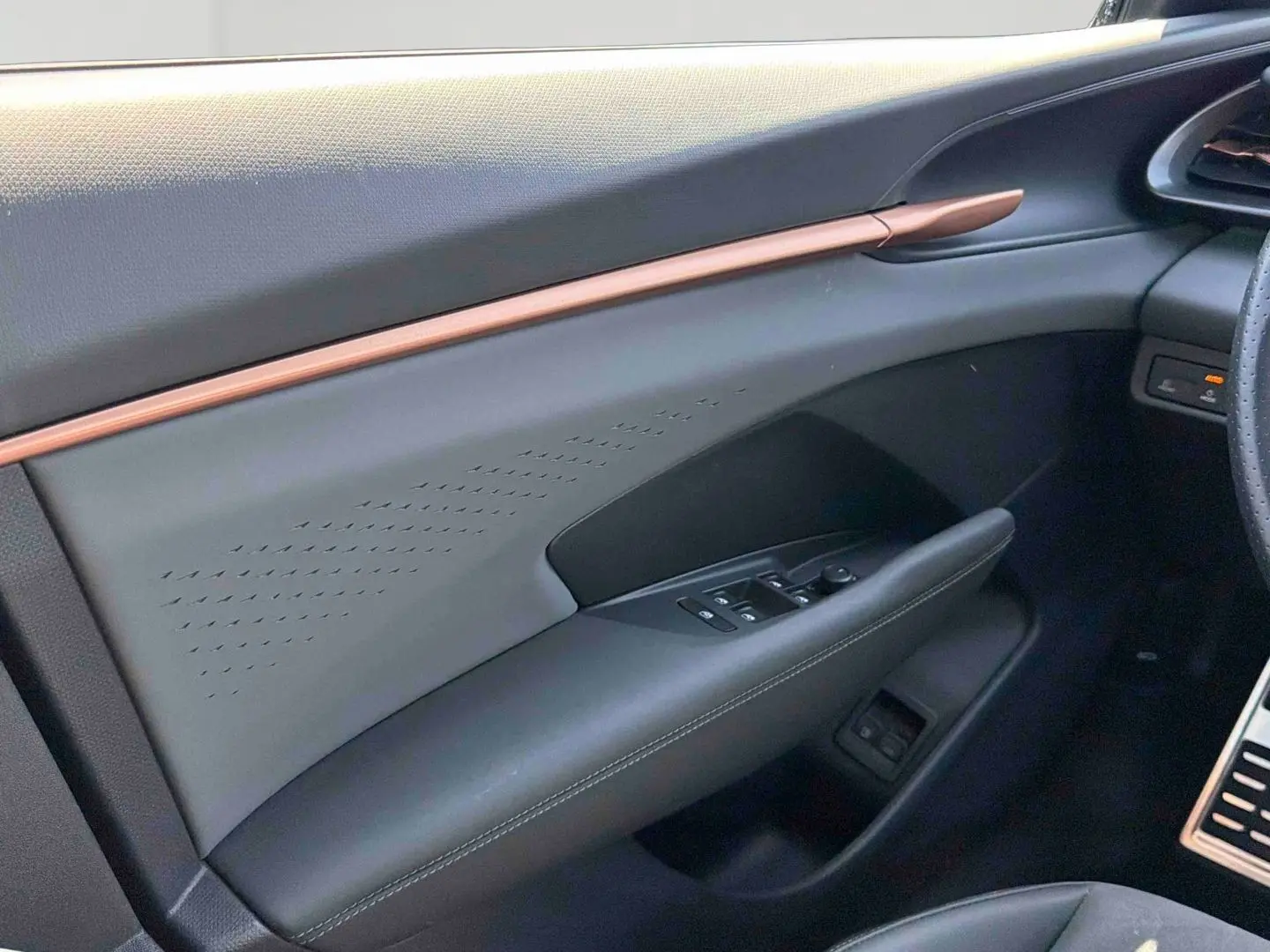 Vue intérieure côté conducteur de la porte CUPRA Terramar 2025 avec garniture noire et bande cuivrée élégante.