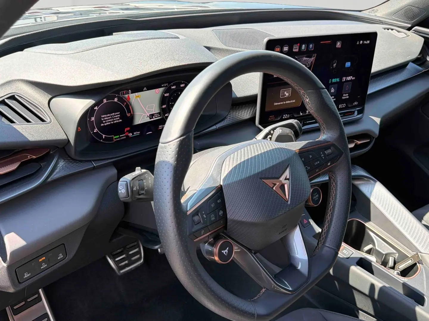 Vue intérieure du tableau de bord et volant cuir noir avec logo CUPRA cuivré, écran tactile HD et finitions texturées grises.