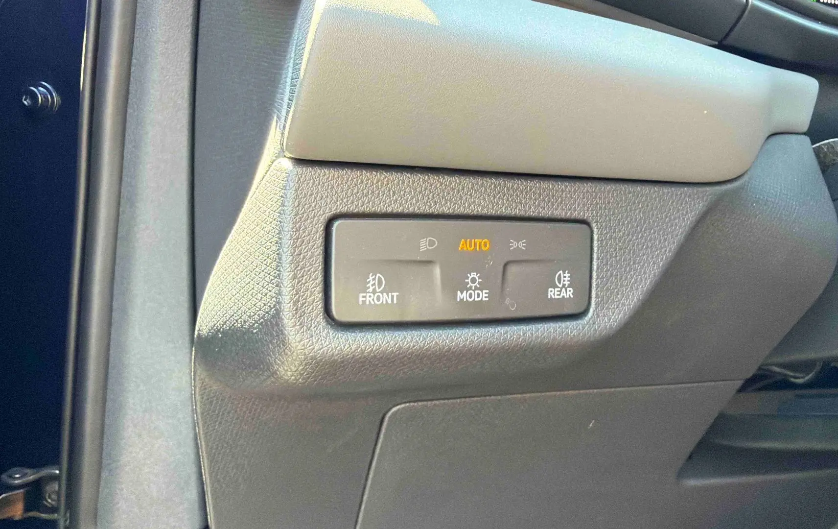 Détail du panneau de commande d’éclairage avec mode automatique sur la partie gauche du tableau de bord d’une CUPRA Terramar bleue.