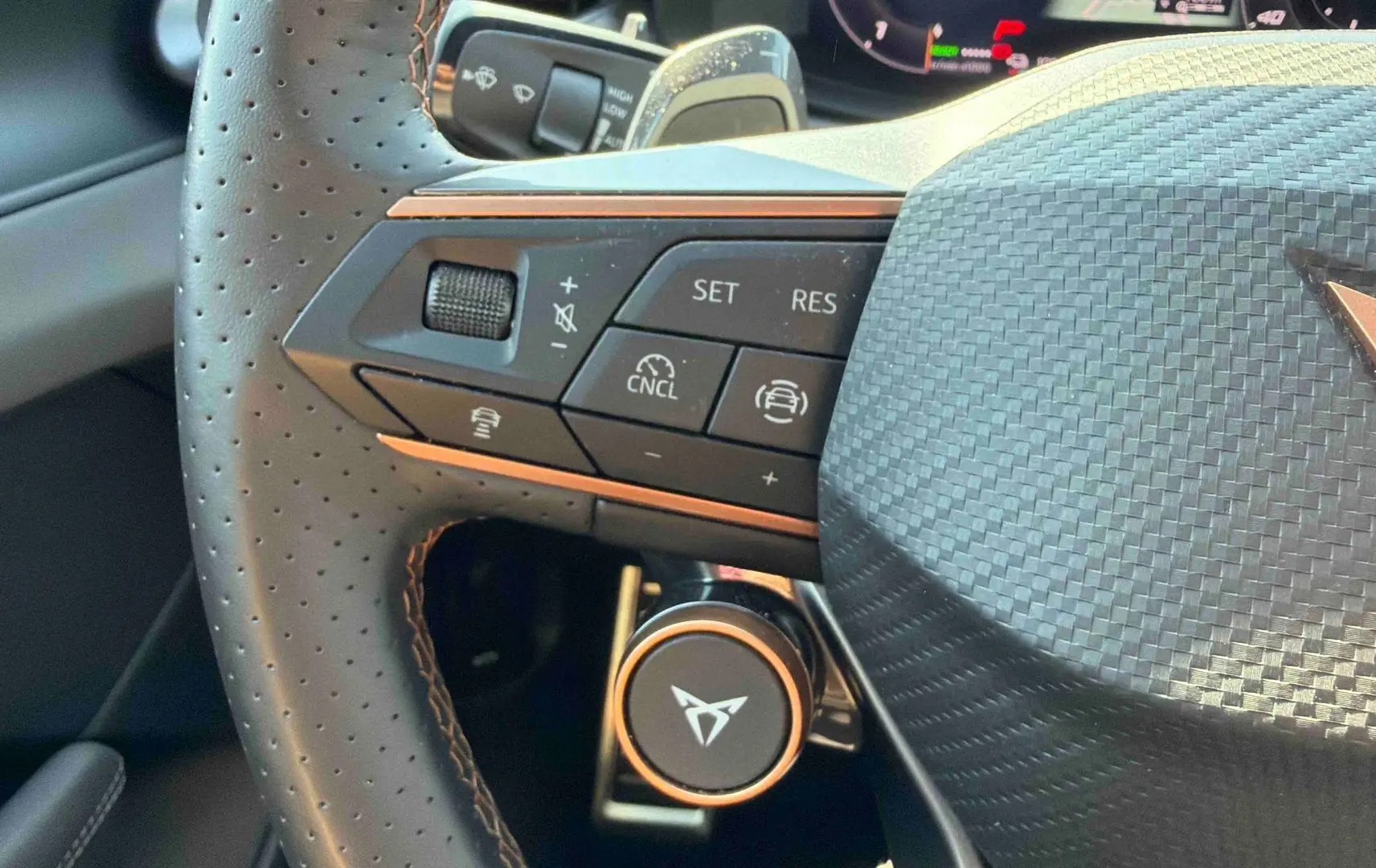 Gros plan sur le volant perforé noir avec logo CUPRA cuivré et commandes multifonctions côté gauche.
