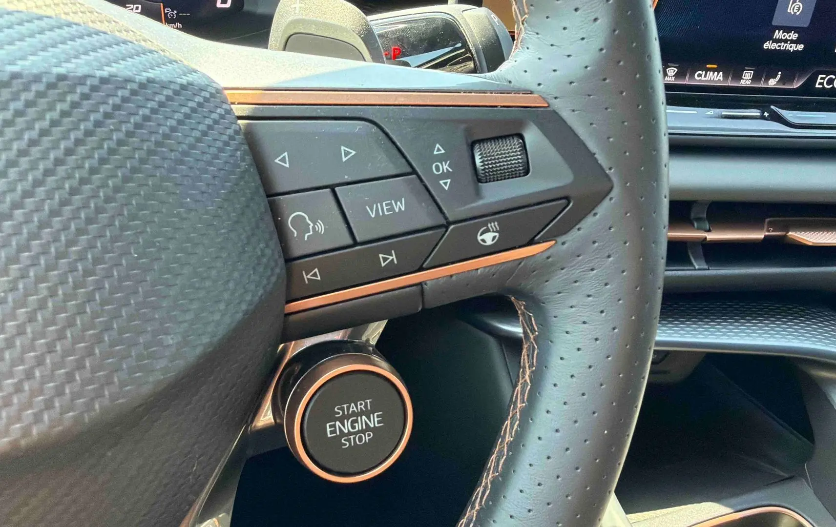 Gros plan sur le volant cuir perforé et les commandes du CUPRA Terramar 2025 avec bouton Start Engine Stop cuivré.