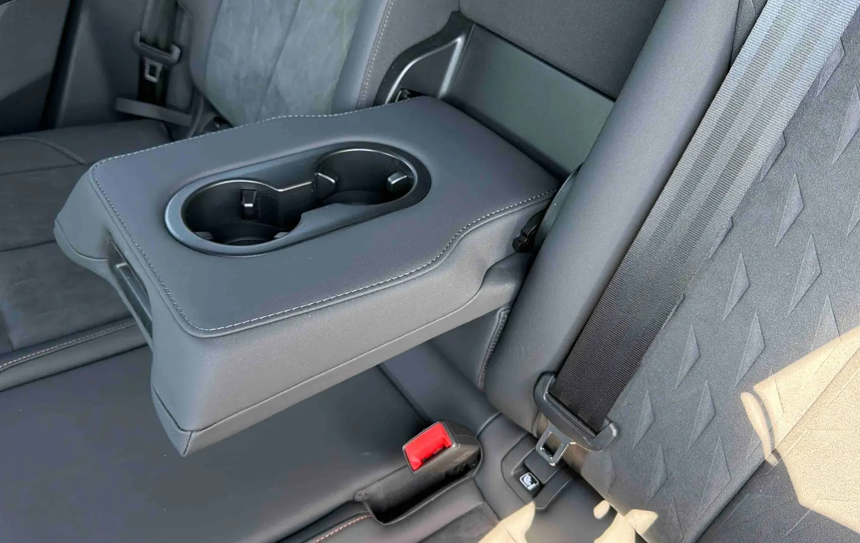 Détail de l'accoudoir central arrière avec porte-gobelets et sellerie suédine noire du CUPRA Terramar 2025.