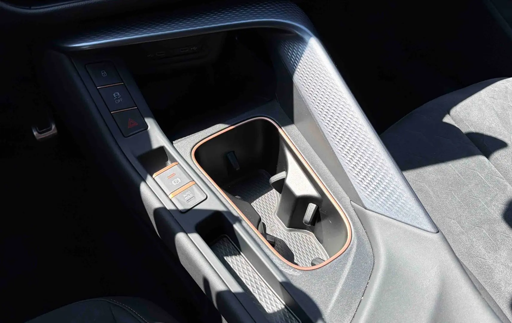 Gros plan sur la console centrale intérieure de la CUPRA Terramar bleu, avec porte-gobelets et finitions cuivrées.