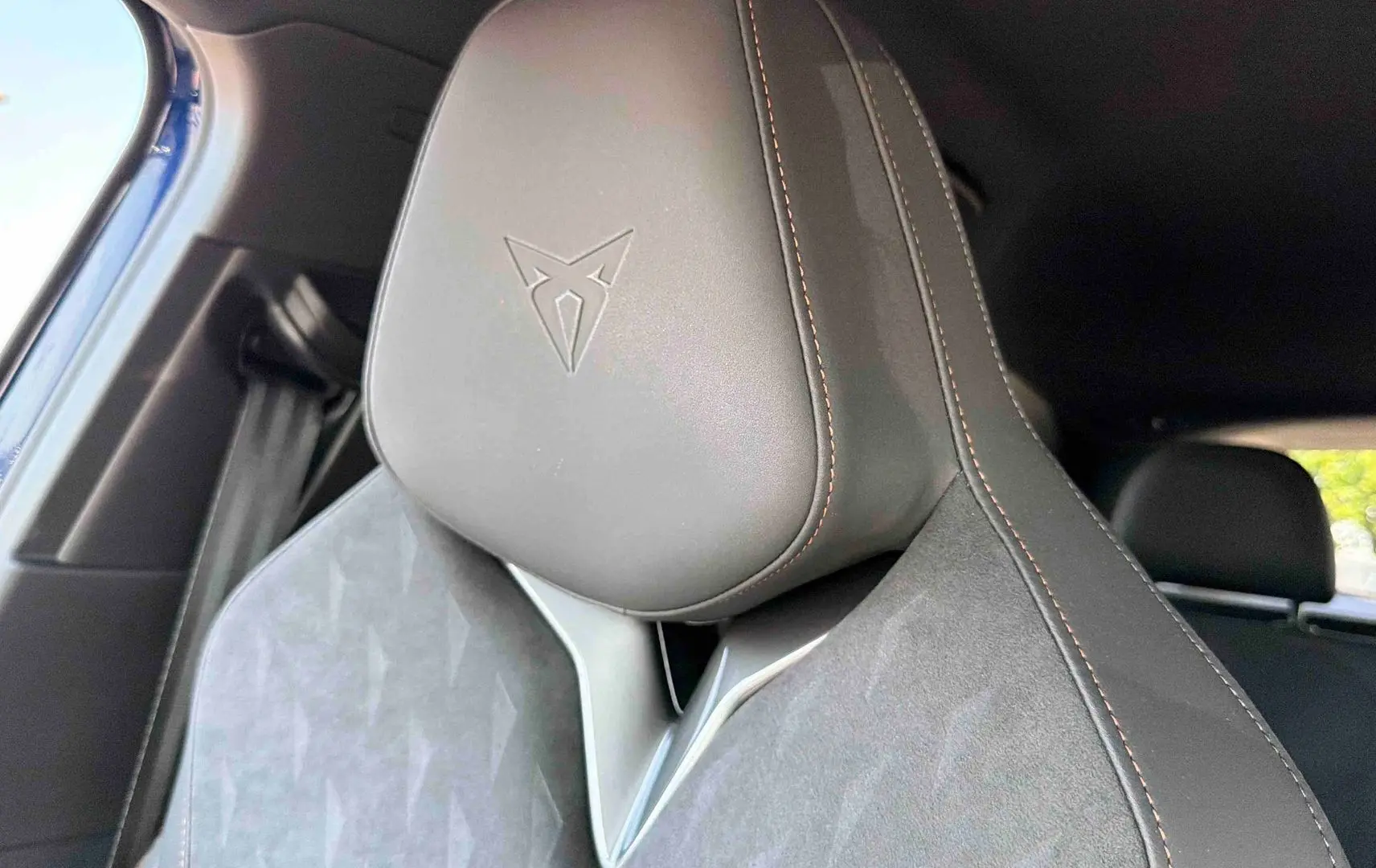 Gros plan sur l'appuie-tête avant gauche en cuir noir avec logo CUPRA embossé et surpiqûres cuivrées.