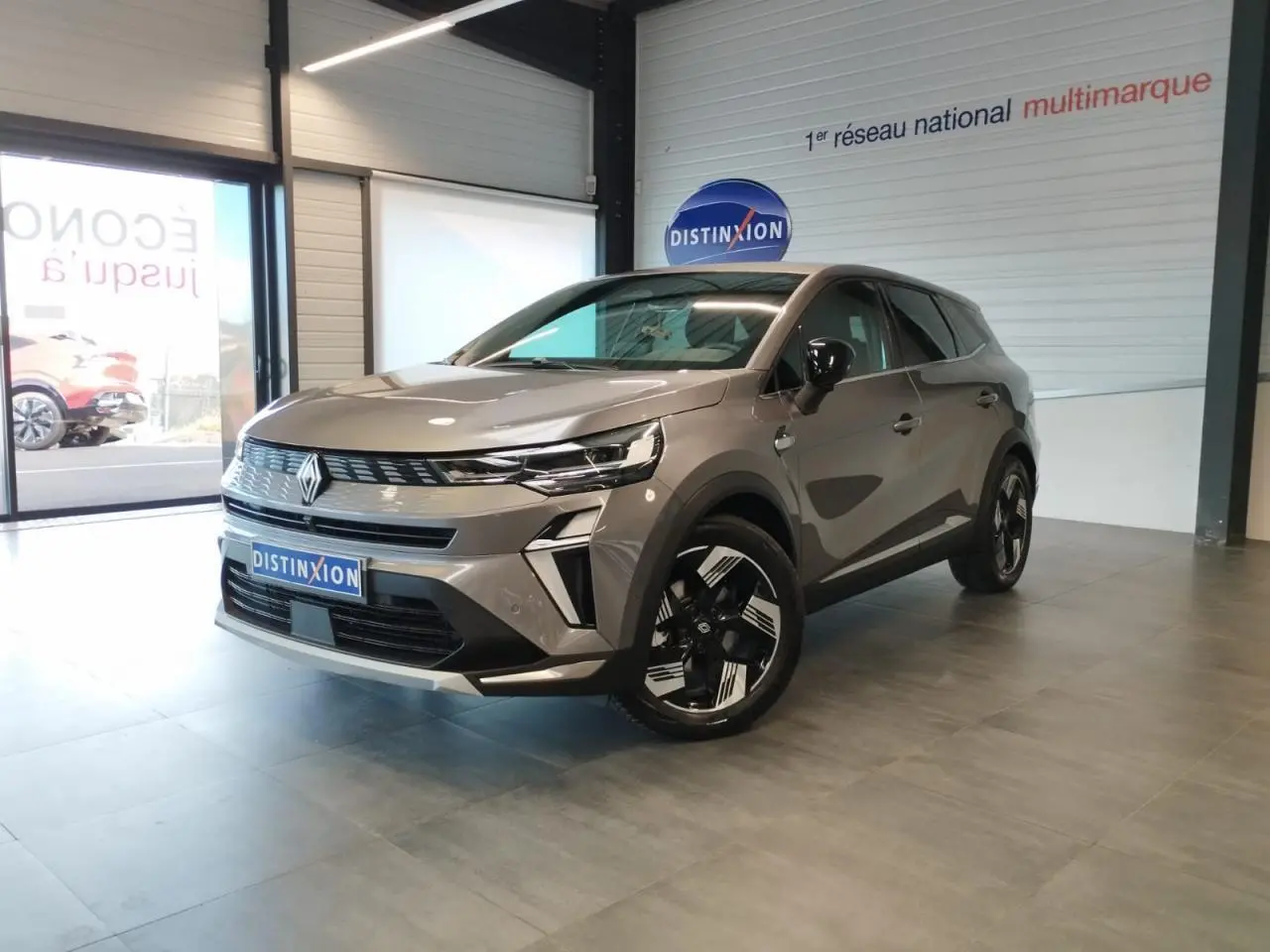 Renault Symbioz gris Cassiopée en 3/4 avant droit, avec jantes 18 pouces et détails noirs brillants en showroom.