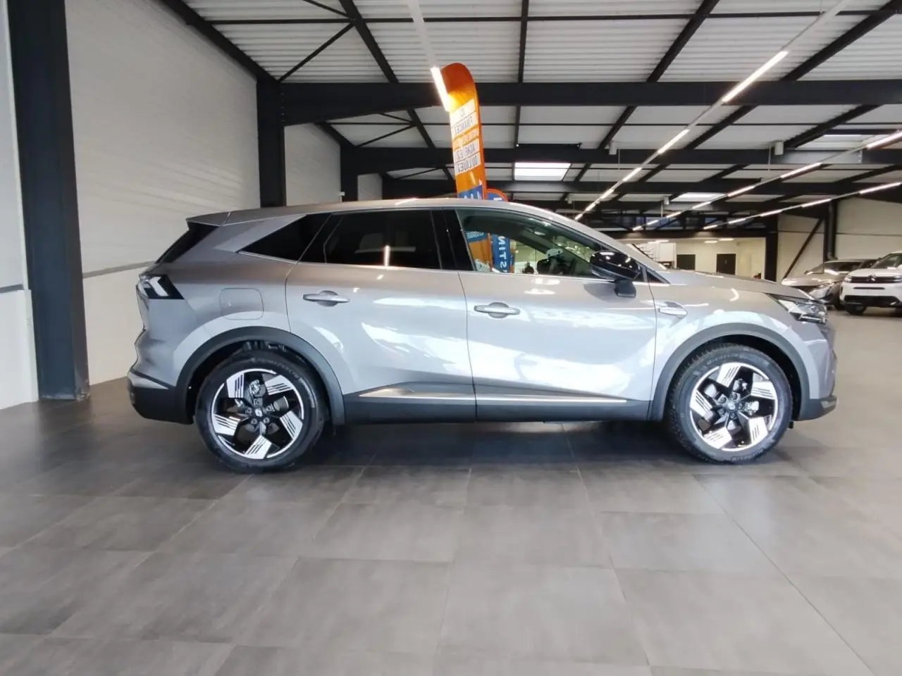 Renault Symbioz 2025 gris Cassiopée en profil droit, avec jantes alliage 19 pouces et vitres teintées.