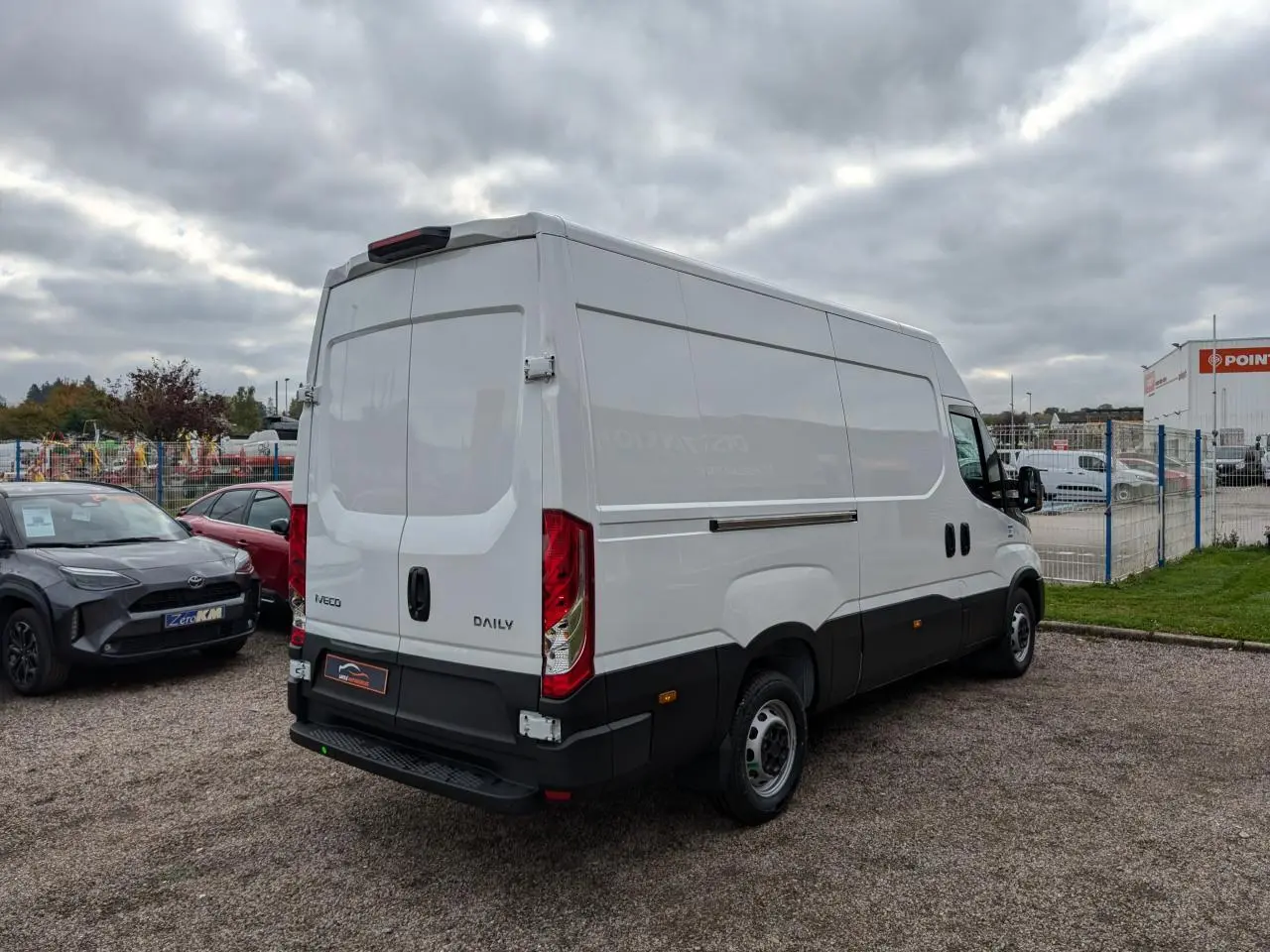 Vue 3/4 arrière droite d’un utilitaire Iveco Daily blanc avec portes arrière battantes et marchepied noir.