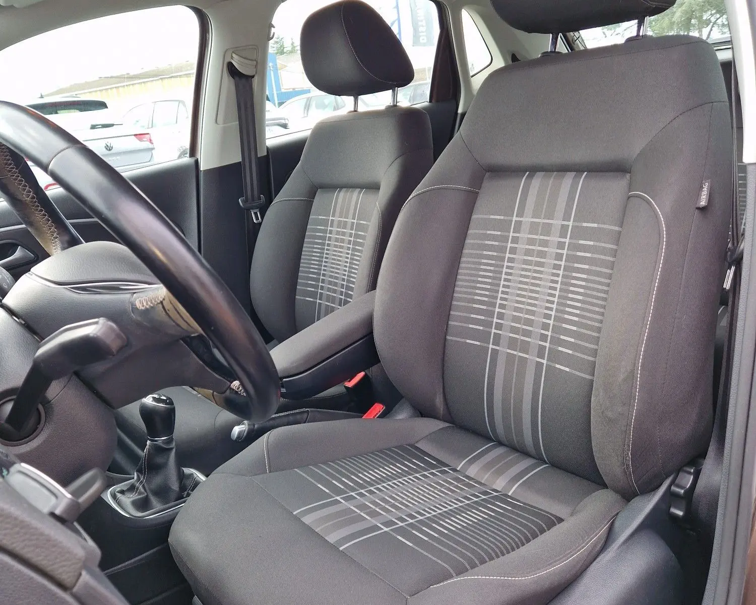 Vue intérieure côté conducteur de la Volkswagen Polo 1.4 TDI 2015, sièges tissu gris avec motifs géométriques.