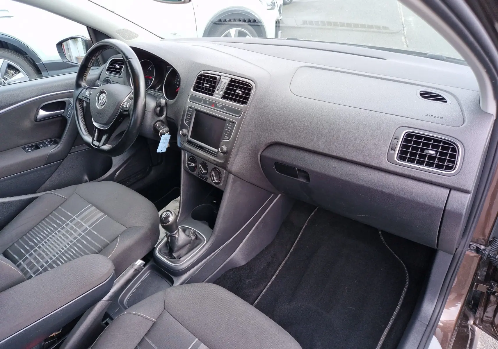 Vue intérieure côté conducteur de la Volkswagen Polo 1.4 TDI brun, montrant le tableau de bord et la boîte manuelle.