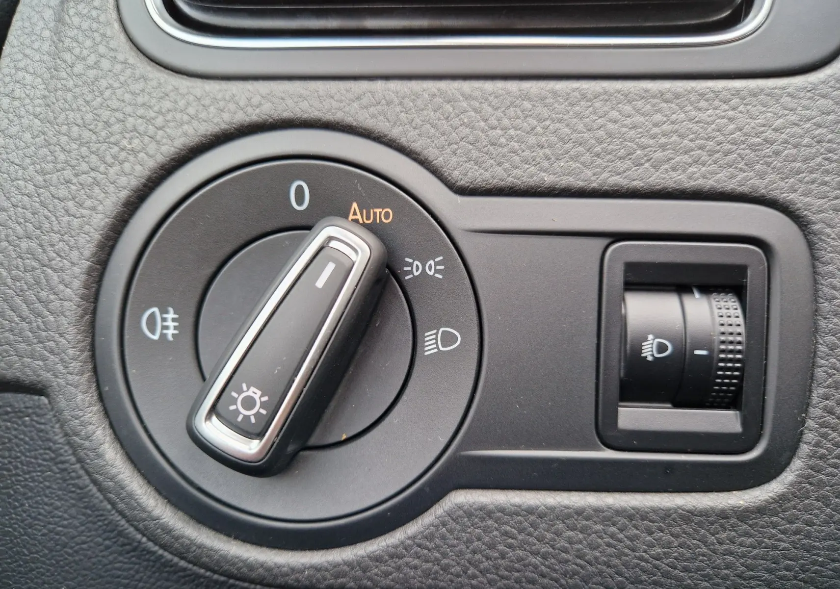 Gros plan sur le bouton de commande des phares et réglage de l’éclairage intérieur d’une Volkswagen Polo 2015 finition Lounge.