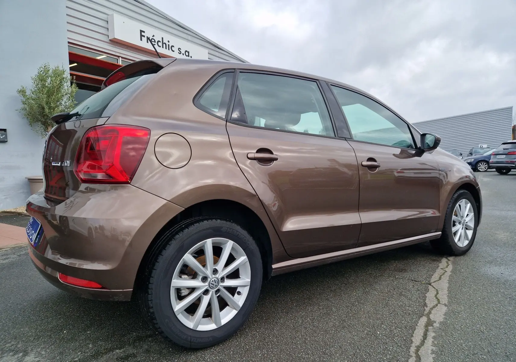 Volkswagen Polo 1.4 TDI brun vue 3/4 arrière droit, jantes alliage et feux arrière distinctifs visibles.
