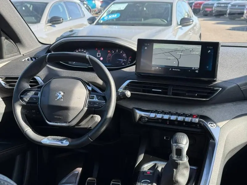 Intérieur du Peugeot 3008 2024 en Gris Platinium, vue du poste de conduite avec volant, tableau de bord numérique et écran central.