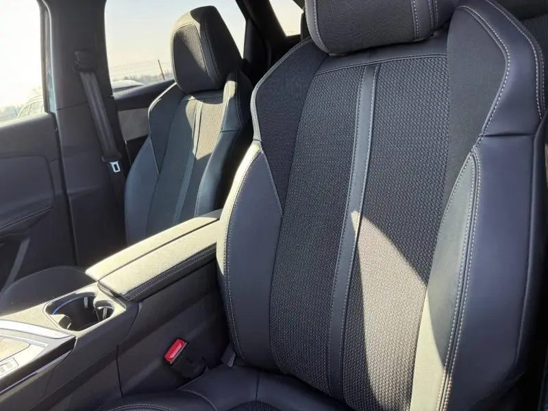 Gros plan sur les sièges avant en tissu et cuir noir du Peugeot 3008 2024, avec surpiqûres contrastantes visibles.