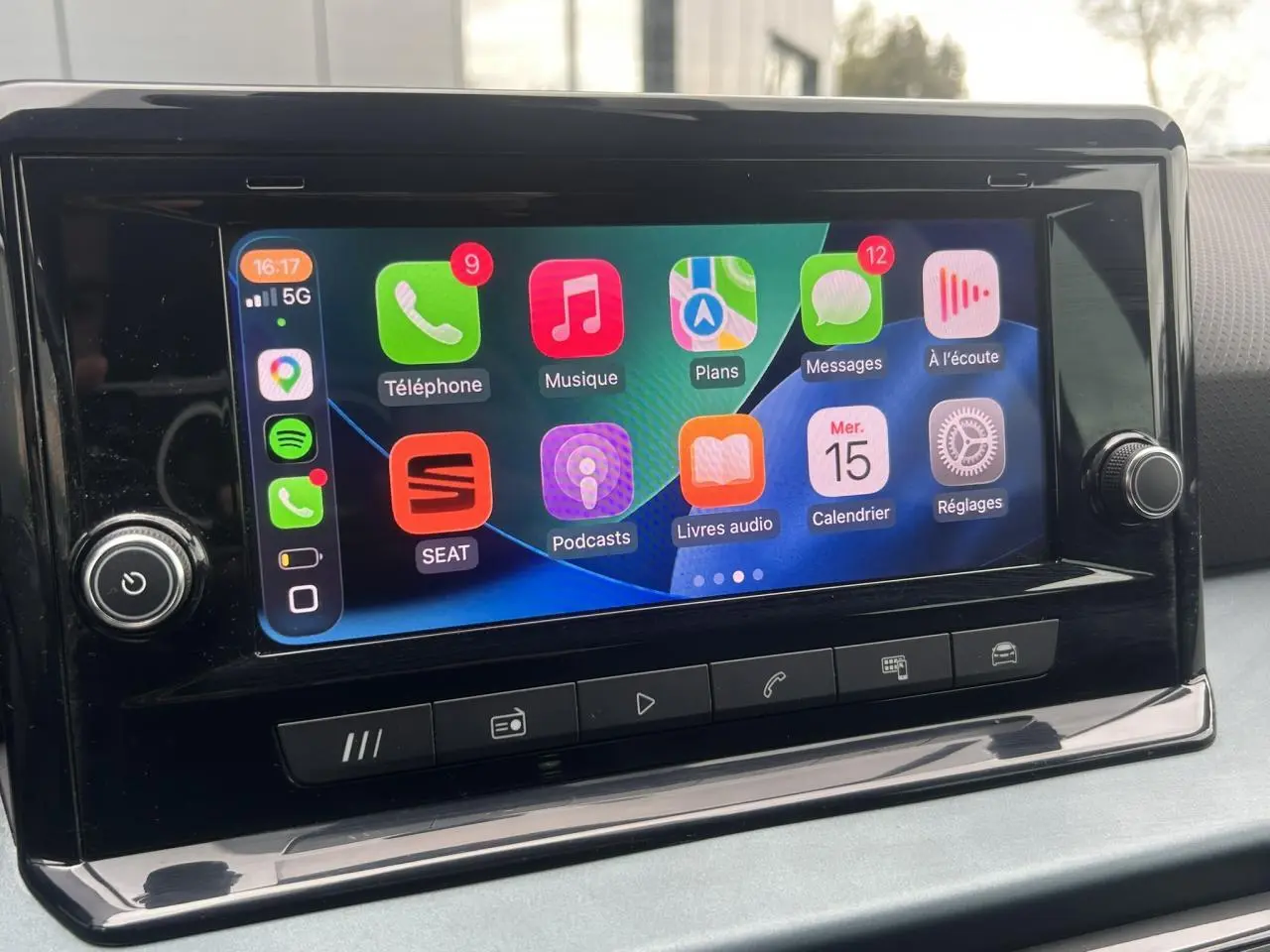 Écran tactile central du tableau de bord du SEAT Arona blanc, affichant l'interface Apple CarPlay colorée.