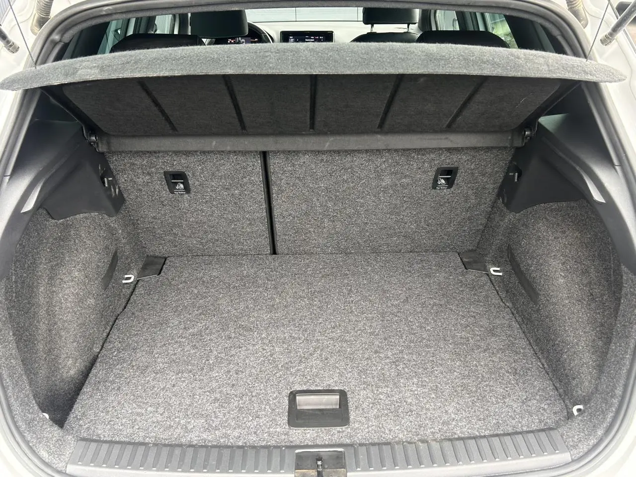 Coffre ouvert vu de l'arrière d'un SEAT Arona blanc Nevada, montrant un espace de chargement propre et spacieux.
