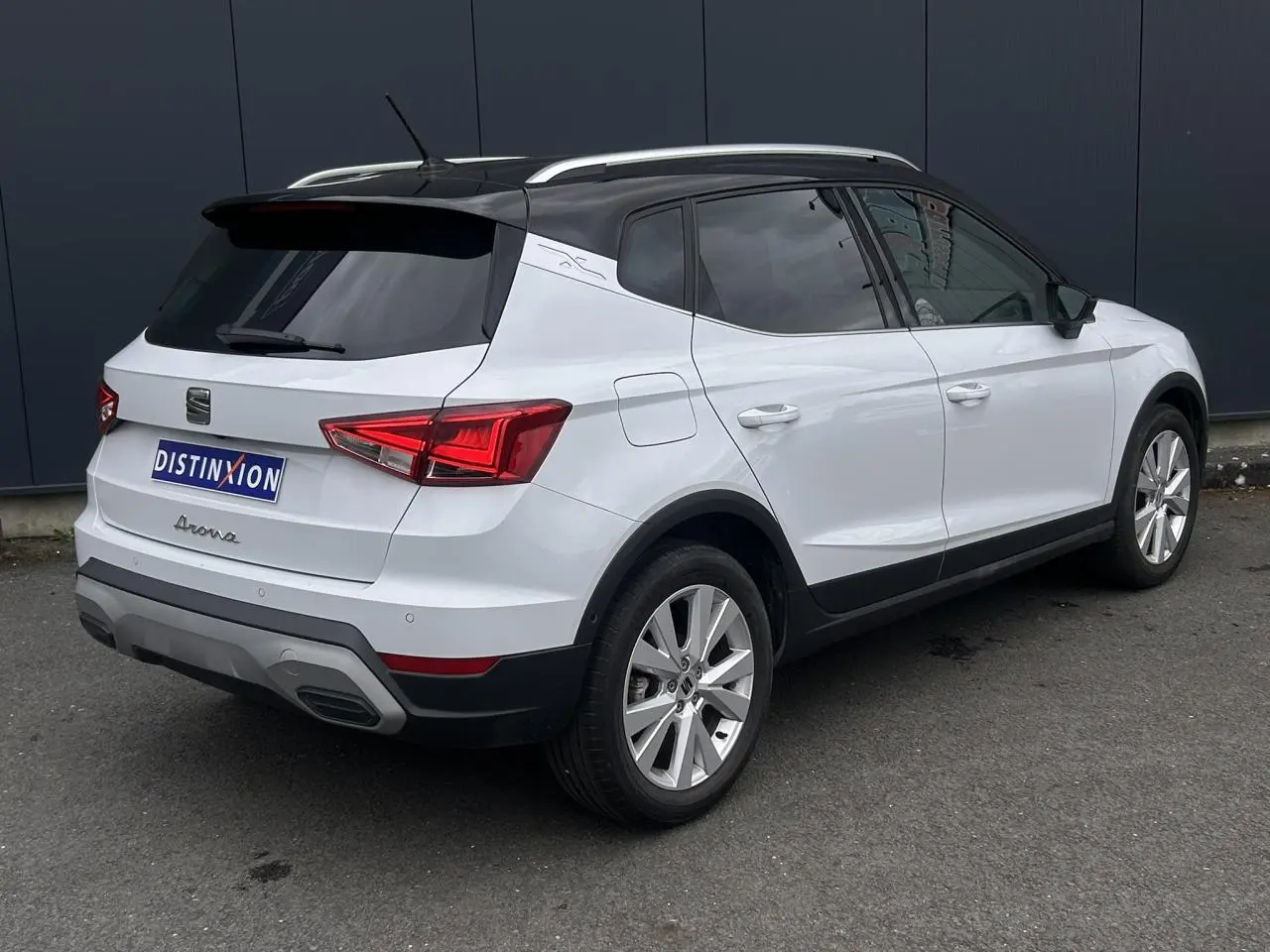 Vue 3/4 arrière droite d'un SEAT Arona blanc Nevada avec toit noir et jantes alliage 17 pouces.
