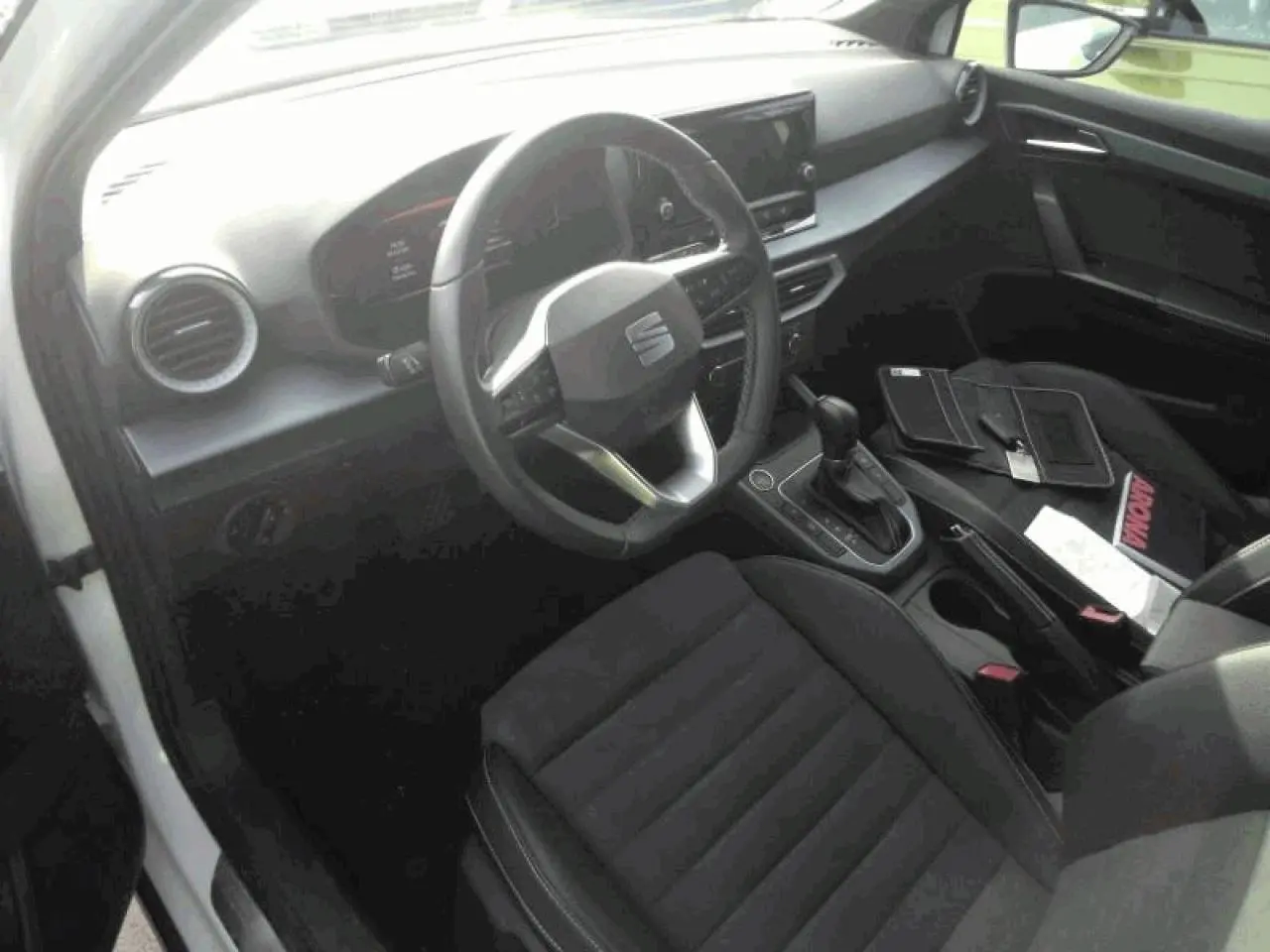 Vue intérieure côté conducteur du SEAT Arona 2025, sellerie suédine noire et tableau de bord moderne avec écran tactile.