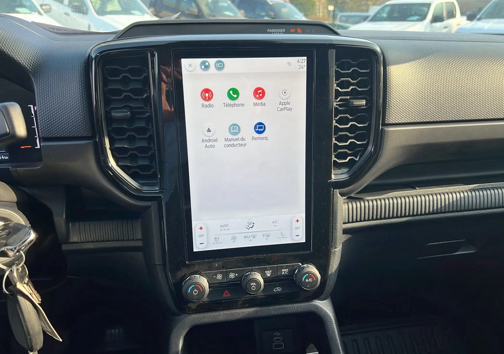 Vue intérieure centrée sur l’écran tactile vertical du tableau de bord du Ford Ranger 2025, avec commandes clim et design noir.