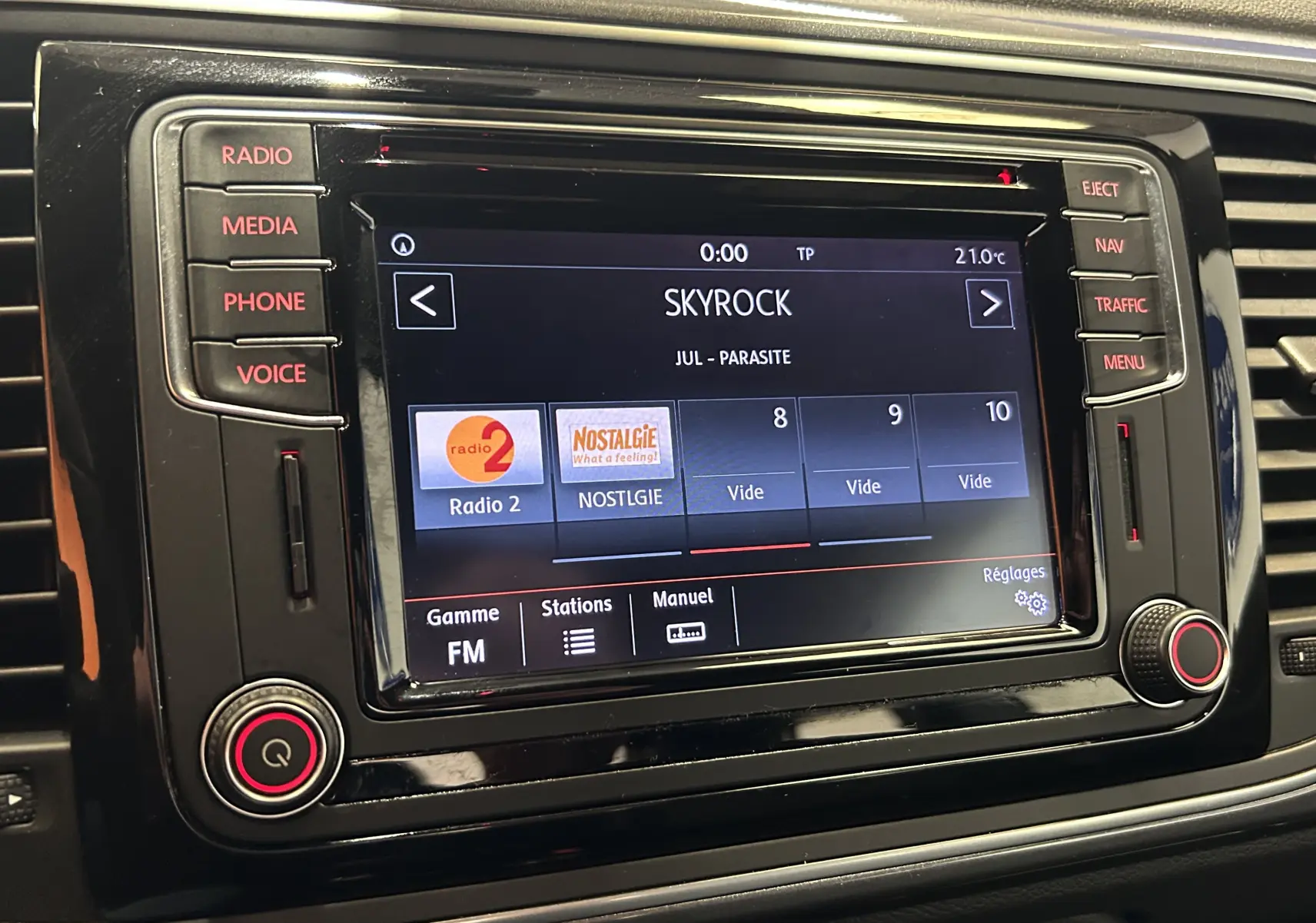 Écran tactile central du tableau de bord de la Volkswagen Coccinelle gris, affichant la radio FM sur Skyrock.