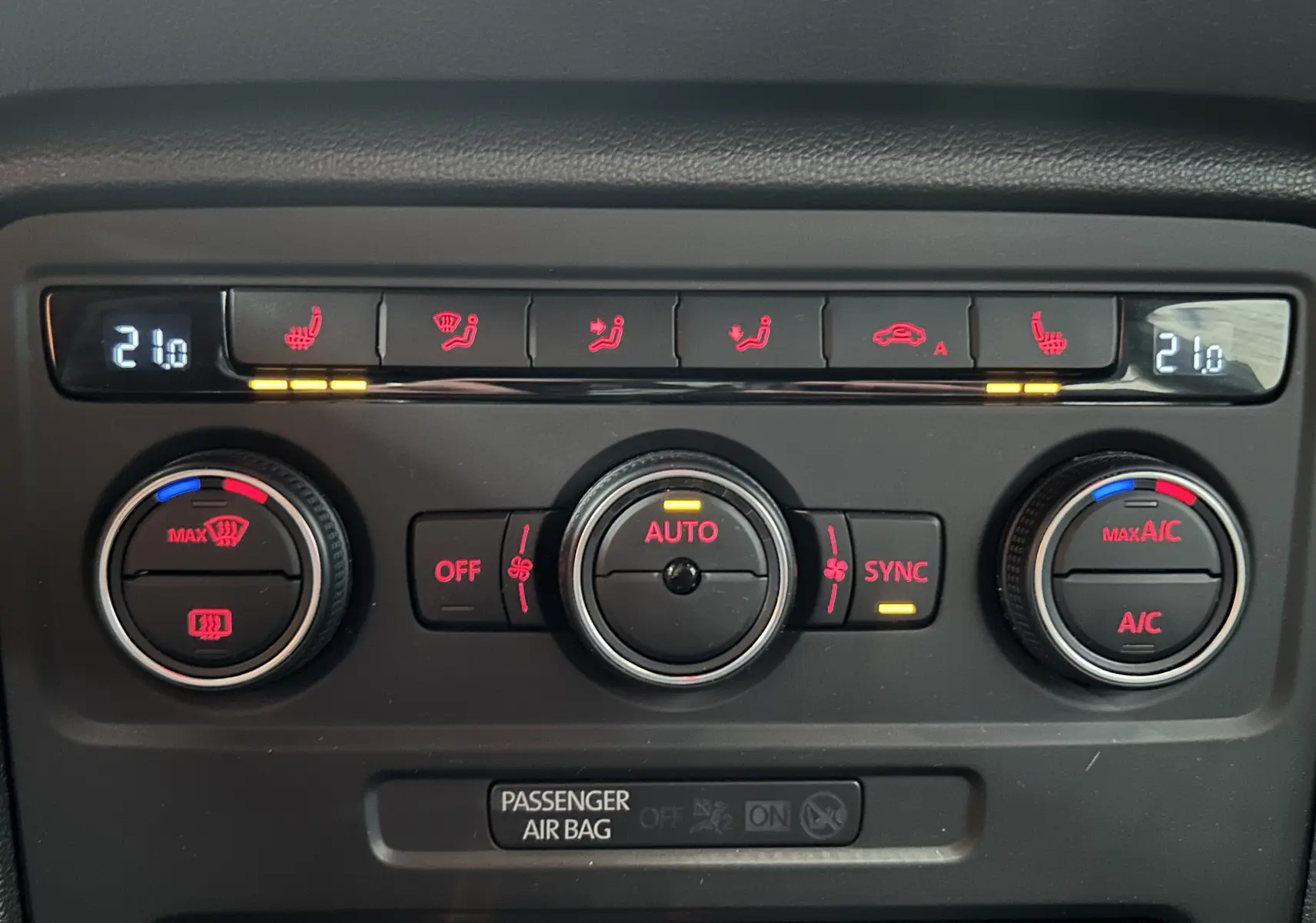 Gros plan sur la console de climatisation de la Volkswagen Coccinelle gris, affichant 21°C avec commandes chauffantes et ventilation.