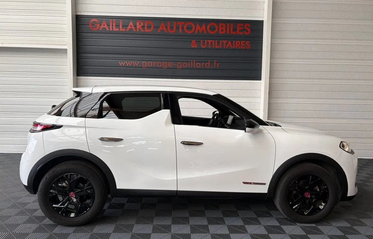 Vue de profil côté gauche d'un DS3 Crossback blanc avec jantes noires et rétroviseurs ton caisse dans un garage.