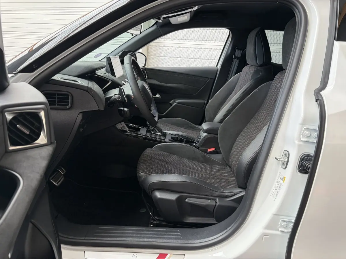 Vue intérieure côté conducteur d’un DS3 Crossback blanc 2022, sièges noirs et tableau de bord moderne avec écran tactile.