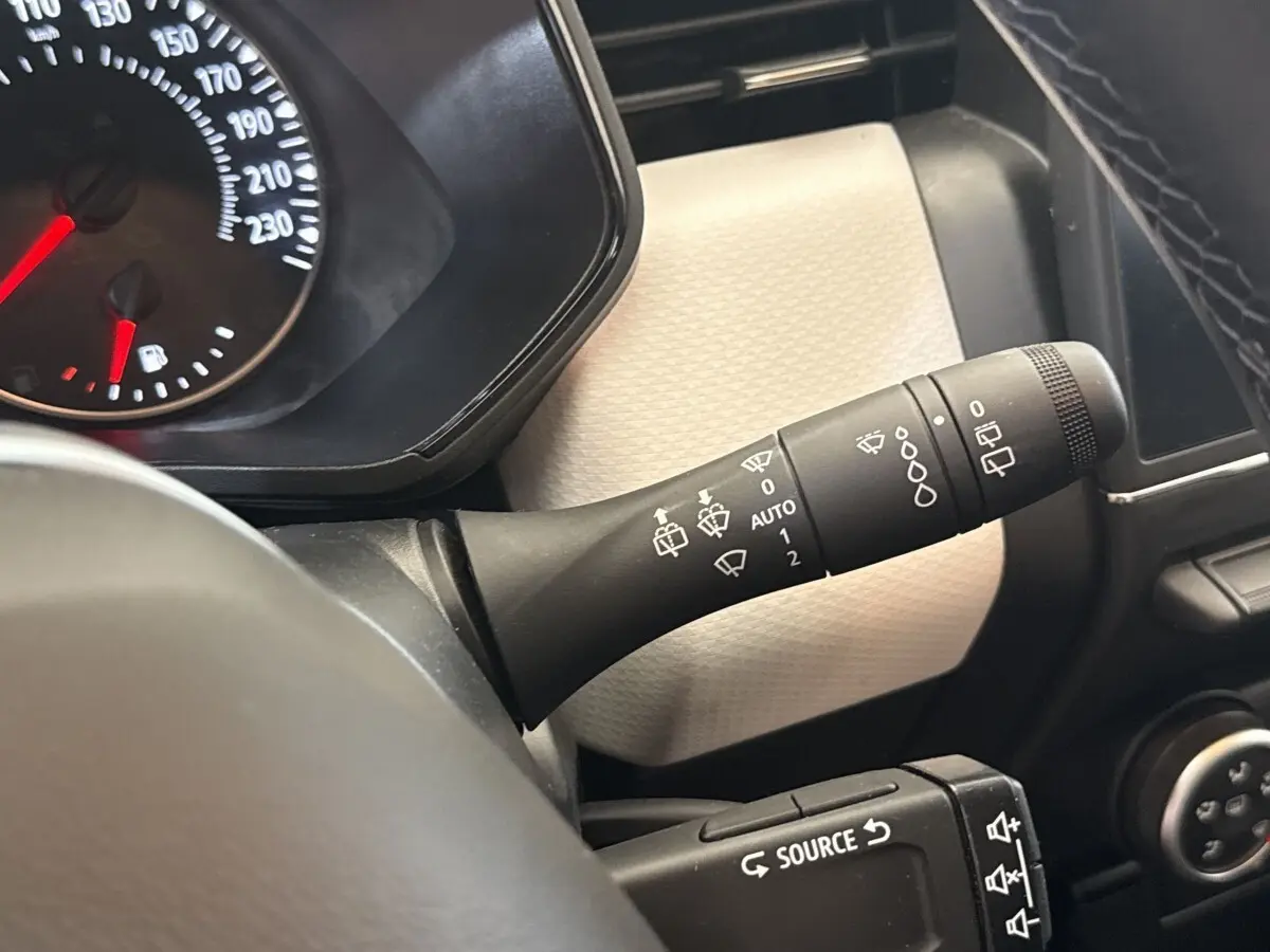 Gros plan sur la manette d’essuie-glace et le compteur de la Renault Clio blanche, vue côté conducteur intérieur.