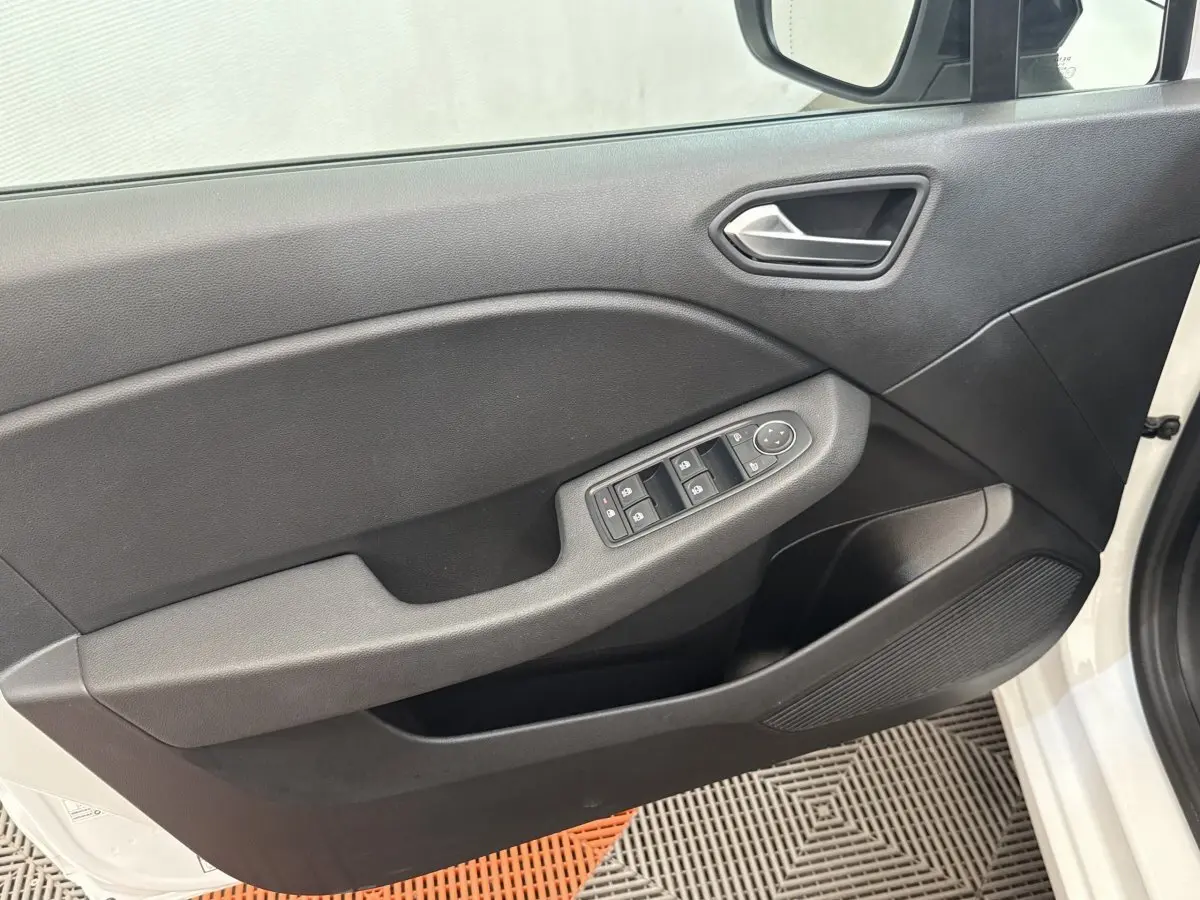 Vue intérieure sur la porte avant gauche noire avec commandes électriques, sur fond extérieur blanc de la Renault Clio Evolution TCe 100 GPL.