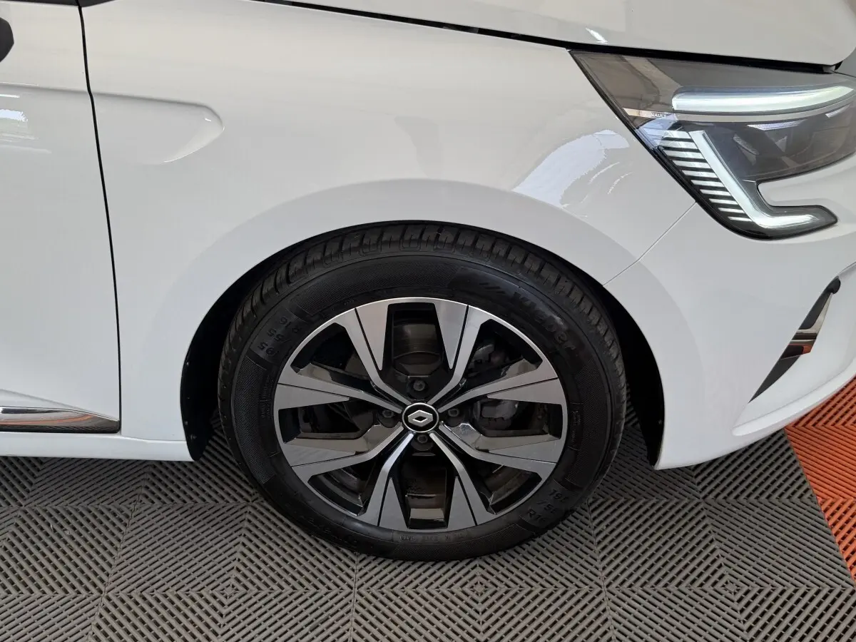 Gros plan sur la roue avant gauche et le phare LED d'une Renault Clio blanche Evolution TCe 100 GPL 2023.