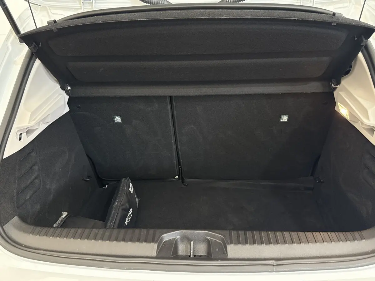 Coffre ouvert vu de l'arrière d'une Renault Clio blanche 2023, intérieur noir avec trousse de secours.