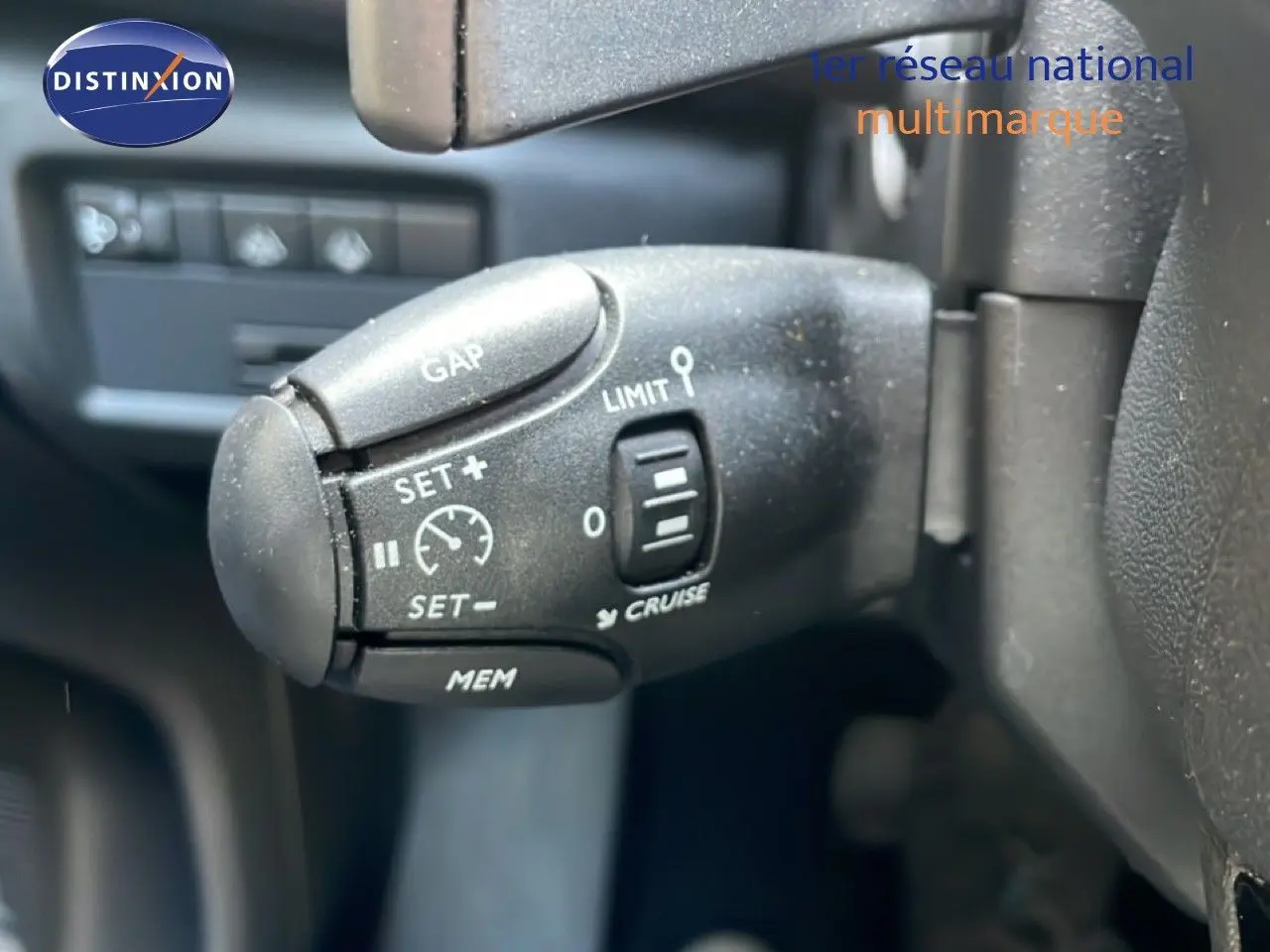 Gros plan sur la commande de régulateur de vitesse à gauche du volant d’un Citroën C5 Aircross bleu Eclipse Metal 2025.