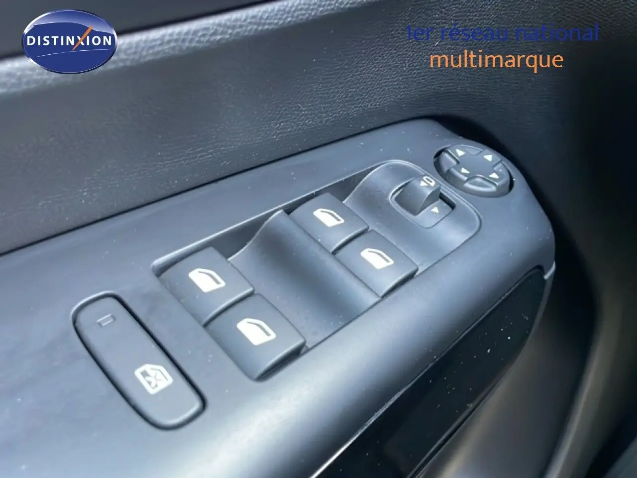 Gros plan sur les commandes des vitres électriques côté gauche intérieur d'un Citroën C5 Aircross bleu Eclipse Metal.