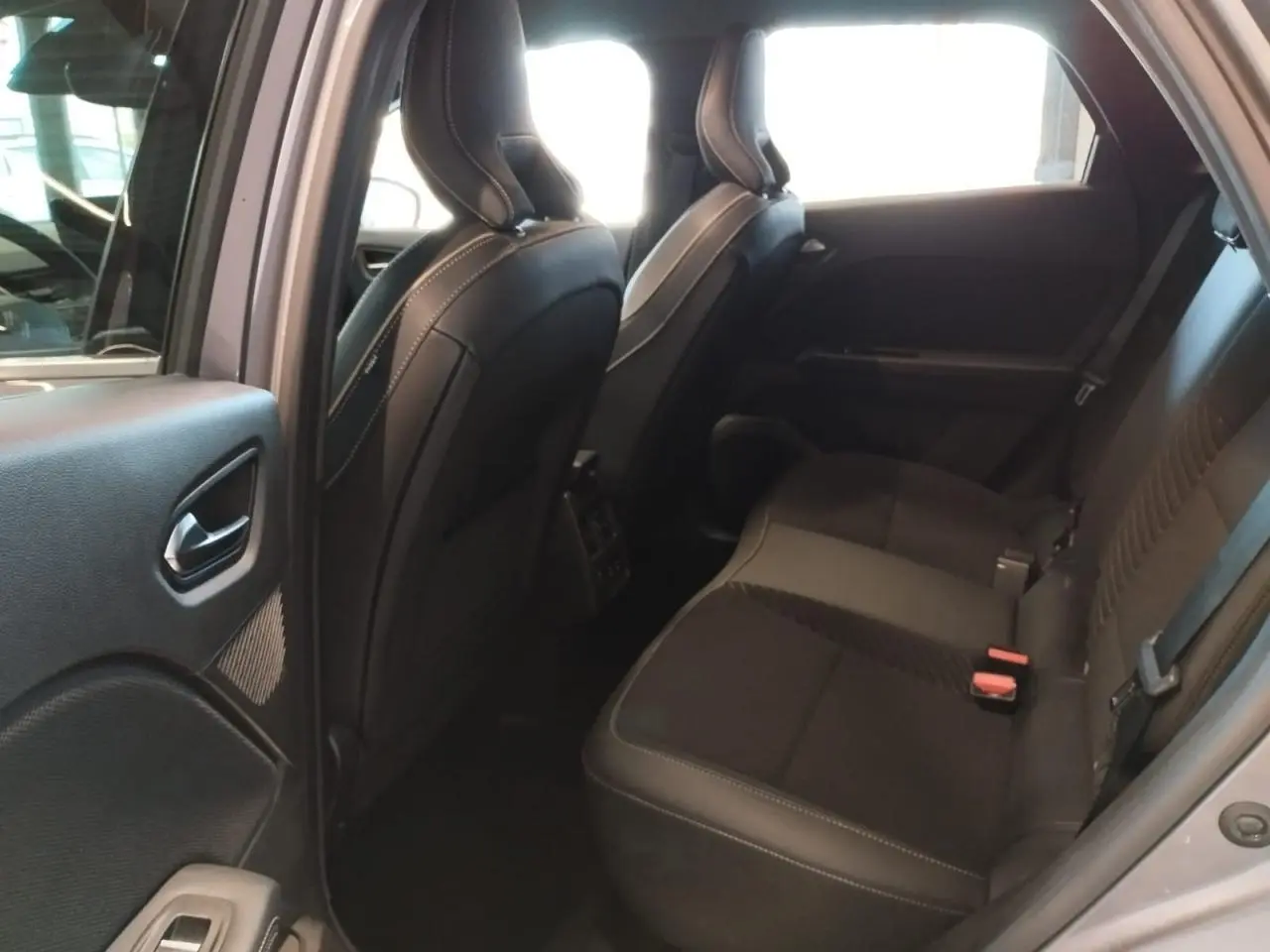 Vue intérieure côté gauche sur la banquette arrière noire du Renault Symbioz gris Cassiopée, avec sièges avant en cuir.