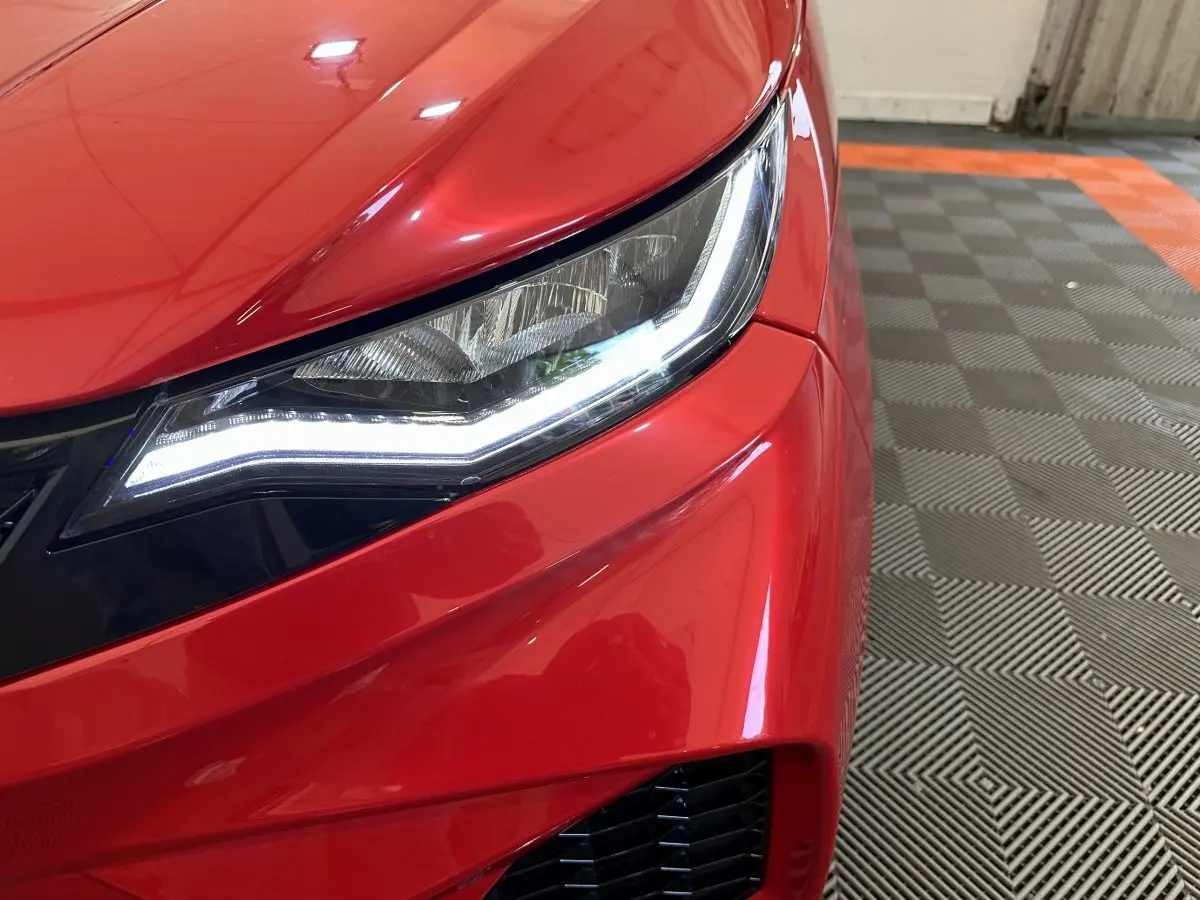 Gros plan sur le phare avant droit de l'AIXAM AMBITION rouge 2026 avec éclairage LED et carrosserie brillante.