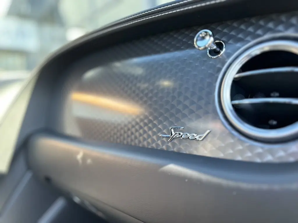 Détail intérieur du tableau de bord noir de la Bentley Continental GT Speed 2015 avec logo "Speed" et sortie d'air ronde chromée.