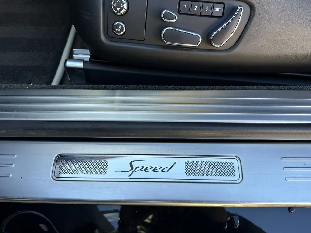 Gros plan sur la plaque de seuil de porte "Speed" et les commandes de siège côté conducteur d'une Bentley Continental GT noire 2015.