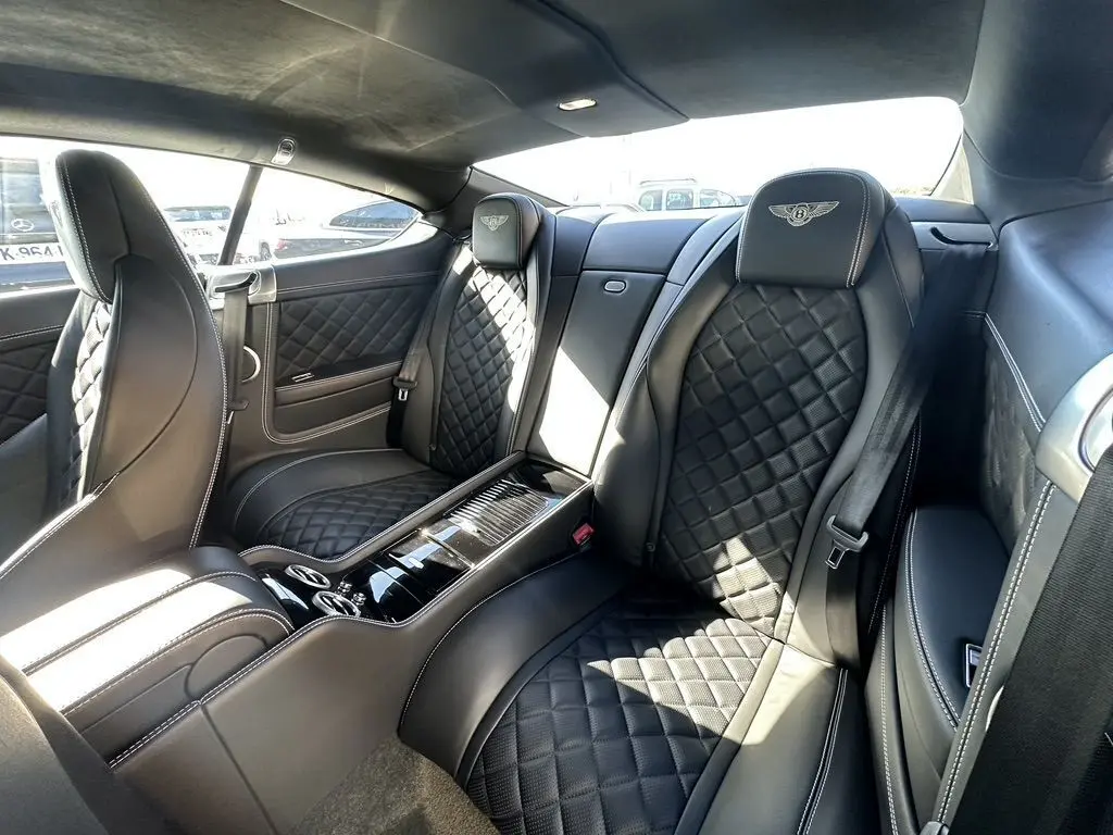 Vue intérieure arrière droite du Bentley Continental GT Speed 2015 noire, sièges en cuir matelassé avec logo Bentley brodé.
