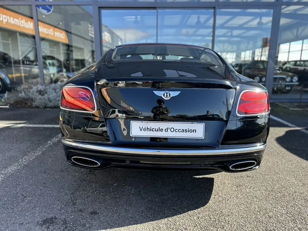 Vue arrière d'une Bentley Continental GT Speed noire de 2015, avec feux rouges et double sortie d'échappement chromée.
