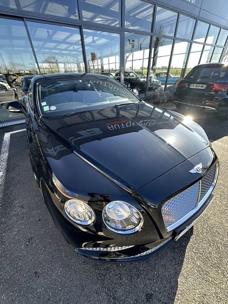 Bentley Continental GT Speed noire vue en 3/4 avant droit, mettant en valeur sa calandre chromée et ses phares ronds.