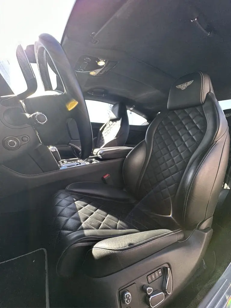 Intérieur noir de la Bentley Continental GT II, vue côté conducteur mettant en valeur les sièges en cuir matelassé avec logo brodé.
